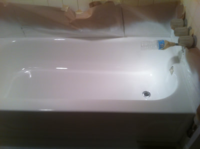 In this image you can see a bathtub undergoing the regazing process. You can see a newly reglazed white bathtub. You can see a paper background protecting the tile background around the bathtub. 