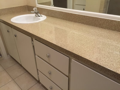 Picture of a bathroom countertop refinished with the Sedona Small color pattern. You can see a bathroom with a white background and cream colored resurfaced countertop. 