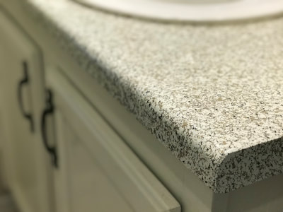 This image shows our moon rock countertop finish. You can see a vanity top with white cabinets and the moon rock pattern. Moon Rock pattern is a white background with small black and gay spots. 