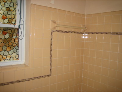 Before picture of a bathroom and more specific the shower area. The ties are outdated and have a pinkish color, from back in the eighties when that was actually trendy. 