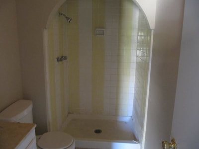 Picture of a bathroom with a closeup of the shower. You see that the shower is dirty and yellowish. The tiles are old and outdated.