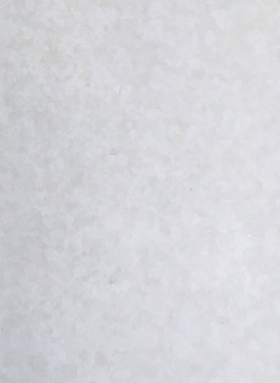 Image of a white dust countertop finish. you can see white with darker colored spots. 