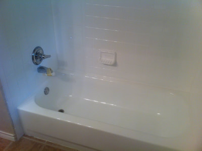 Picture of a bathtub that looks very white and bright. You see the tiles, they are shiny white as well, creating that open space and modern look and feel. 
