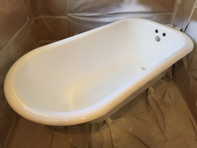 Picture of a bathtub that is in the process of refinishing. The tiles and the walls around the tub are all covered so that they don't get covered with the finish they use for the tub. 
