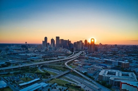picture of the city of Dallas Texas. You can see an overview of the city with the sun set in the background.