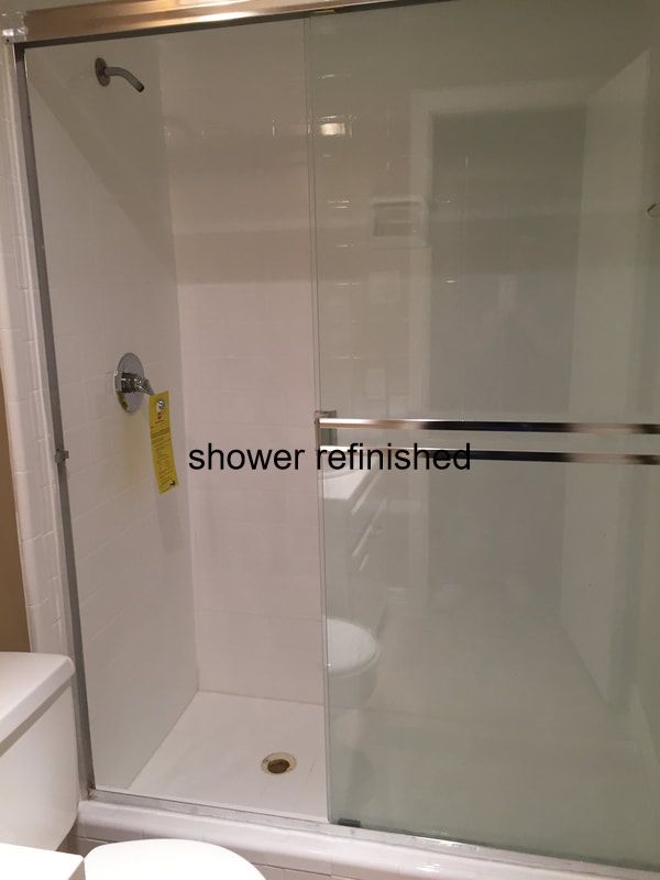 picture of renovated shower. You can see a glass door and white shower interior 