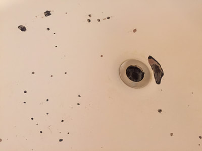 Closeup picture of a bathtub that is damaged. You can see rusty spots on the tub. 