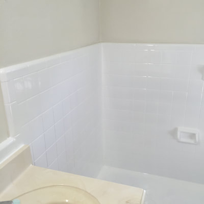 After picture of a bathroom shower that just new white tiles. 