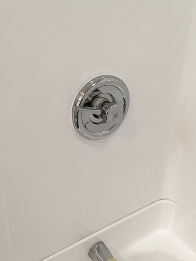 Picture of a restored fiberglass bathroom wall where the water connection is placed. It is finished neatly and look like it's done professional. 