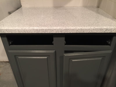 Picture of refinished white kitchen countertop. The white countertop stands in contrast with the dark grey cabinets, creating a dramatic yet modern look. 