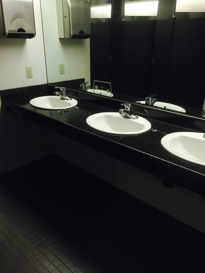 Picture of a bathroom countertop with three sinks that are refinished in a very dark finish, that creates a dramatic look. 