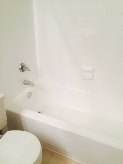 After picture of a bright white bathroom, with new white tiles installed and the bathtub freshly reglazed.