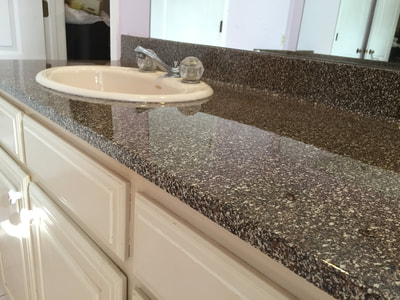 Picture of a bathroom countertop refinished in a darker finish, which stands in contrast with the lighter cabinets. 