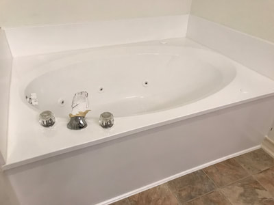 After picture of a white jetted tub  that has now been reglazed. There are no more signs of caulk and it looks nice and shiny! 
