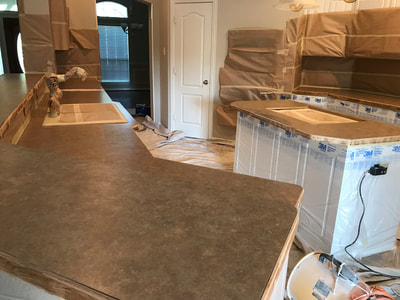A before picture of brown kitchen countertops that are being refinished. Everything is covered up but the countertops. 