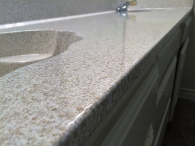 Picture of a bathroom countertop refinished. The color of the finish is greyish. 