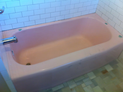 In this image you can a see a before picture of a bathtub before refinishing. You can see a dull pink bathtub. With a white tile background. 