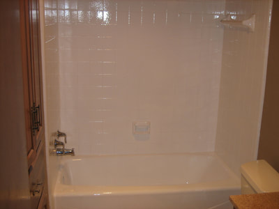 Picture of a bathtub that looks bright white and shiny! Also the tiles look beautifully white! The entire tub and tiles got a makeover when they got refinished!