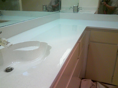 This image shows a resurfaced bathroom countertop using the white dust color pattern. You can see a white countertop with a shell sink. 
