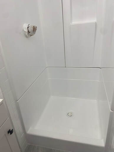 Picture of a close up of a newly refinished shower. You can see the resurfacing project is almost done as the only thing left to do is re-attaching the shower knob. 